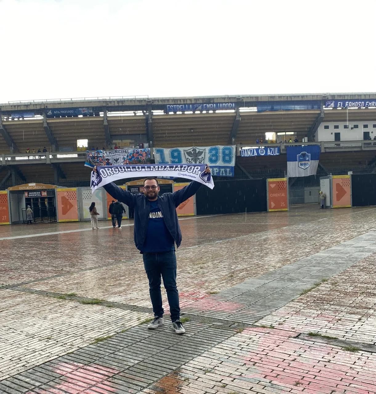 Hincha levantando la bufanda de Orgullo Embajador frente a la tribuna oriental de El Campín